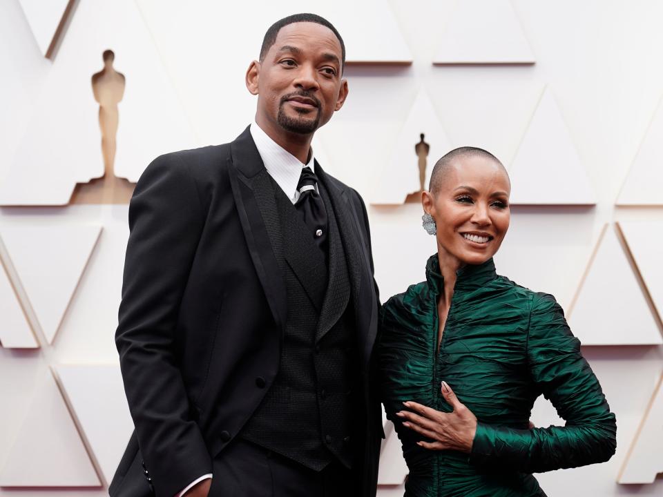 Will in a black suit and Jada in a shiny green long-sleeve dress.