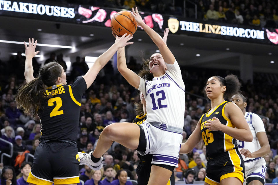Northwestern guard Casey Harter (12) shoots against Iowa guard Taylor McCabe, left, guard Caitlin Clark and forward Hannah Stuelke, right, during the second half of an NCAA college basketball game in Evanston, Ill., Wednesday, Jan. 31, 2024. Iowa won 110-74. (AP Photo/Nam Y. Huh)