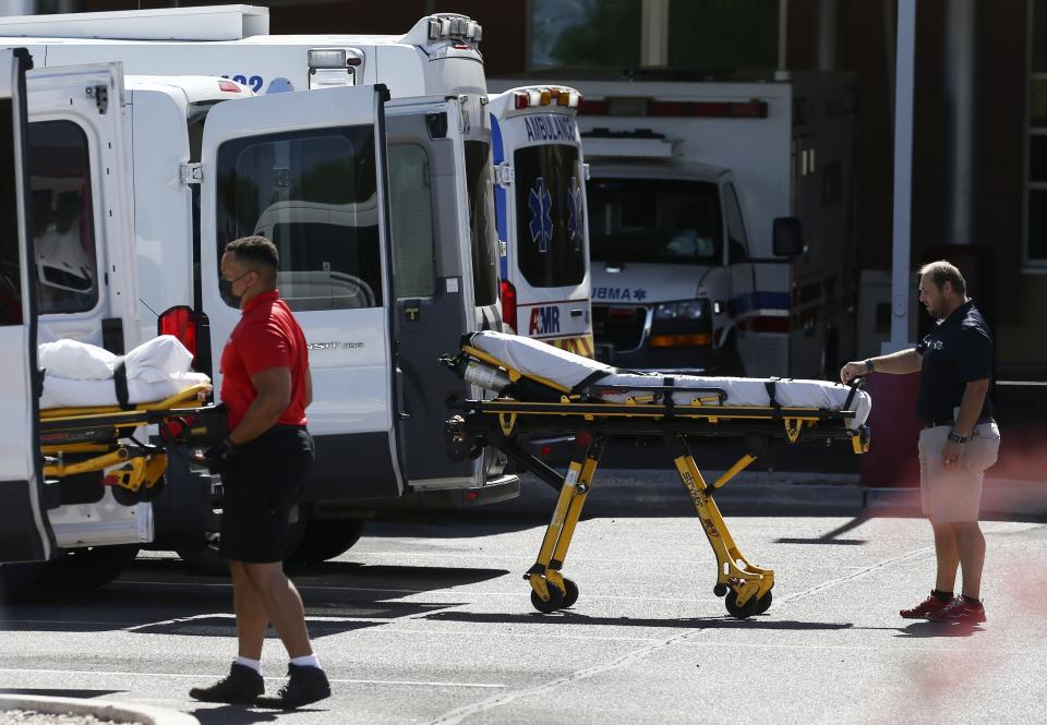 FILE - In this June 16, 2020, file photo, medical transports and ambulances are parked outside the emergency-room entrance at Banner Desert Medical Center, in Mesa, Ariz. The number of deaths per day from the coronavirus in the U.S. has fallen in recent weeks to the lowest level since late March, even as states increasingly reopen for business. But scientists are deeply afraid the trend may be about to reverse itself. (AP Photo/Ross D. Franklin, File)