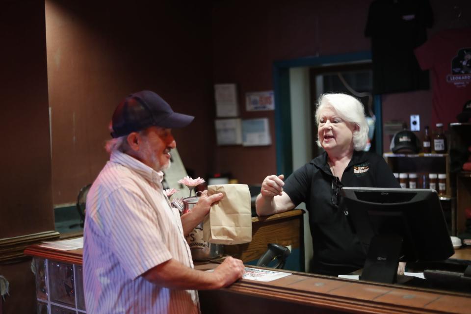 Loretta Hopper, who has worked for Leonard’s for 52 years, hands an order to customer John Huffman at the counter inside of 101-year-old Leonard’s BBQ before they move later this month on August 16, 2023 at 5465. Fox Plaza Drive in Memphis, Tenn.