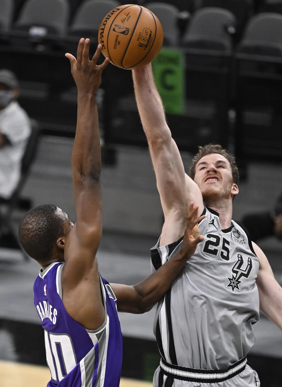 San Antonio Spurs' Jakob Poeltl (25) blocks a shot by Sacramento Kings' Harrison Barnes during the second half of an NBA basketball game on Monday, March 29, 2021, in San Antonio. (AP Photo/Darren Abate)