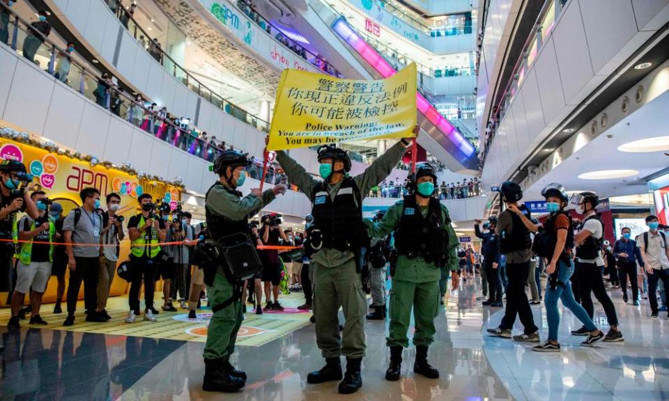 Police hold up a warning flag during a pro-democracy demonstration at a mall in Hong Kong on Monday.