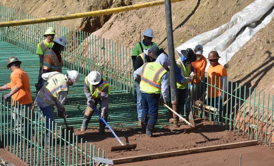 Construction workers Monday, Feb. 14, 2022, in Fort Collins, Colo., smooth concrete poured for a new pedestrian/bicycle underpass that will go under a widened South Timberline Road.