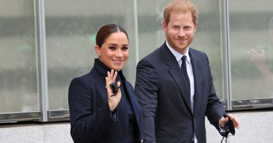 Prince Harry and Meghan Markle wave at the camera as they arrive to an event.