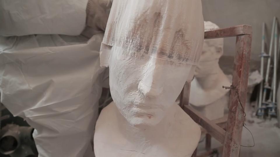 A white bust that looks like marble is pulled to reveal its made of connected paper