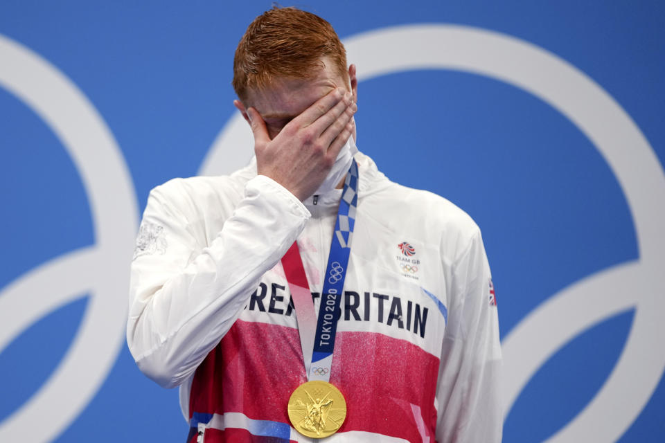 Tom Dean of Britain covers his face after receiving his gold medal on the podium after winning the men's 200-meter freestyle at the 2020 Summer Olympics, Tuesday, July 27, 2021, in Tokyo, Japan. (AP Photo/Matthias Schrader)