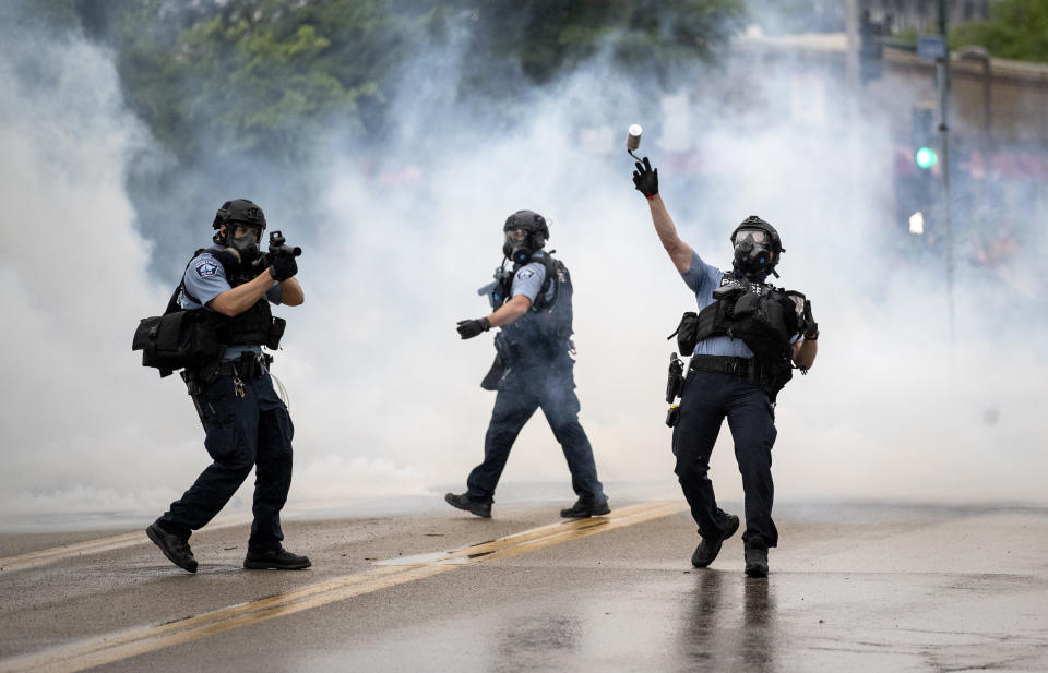 A police officer throws a tear gas canister towards protesters at the Minneapolis 3rd Police Precinct, following a rally for George Floyd on Tuesday, May 26, 2020, in Minneapolis. Four Minneapolis officers involved in the arrest of Floyd, a black man who died in police custody, were fired Tuesday, hours after a bystander's video showed an officer kneeling on the handcuffed man’s neck, even after he pleaded that he could not breathe and stopped moving. (Richard Tsong-Taatarii/Star Tribune via AP)