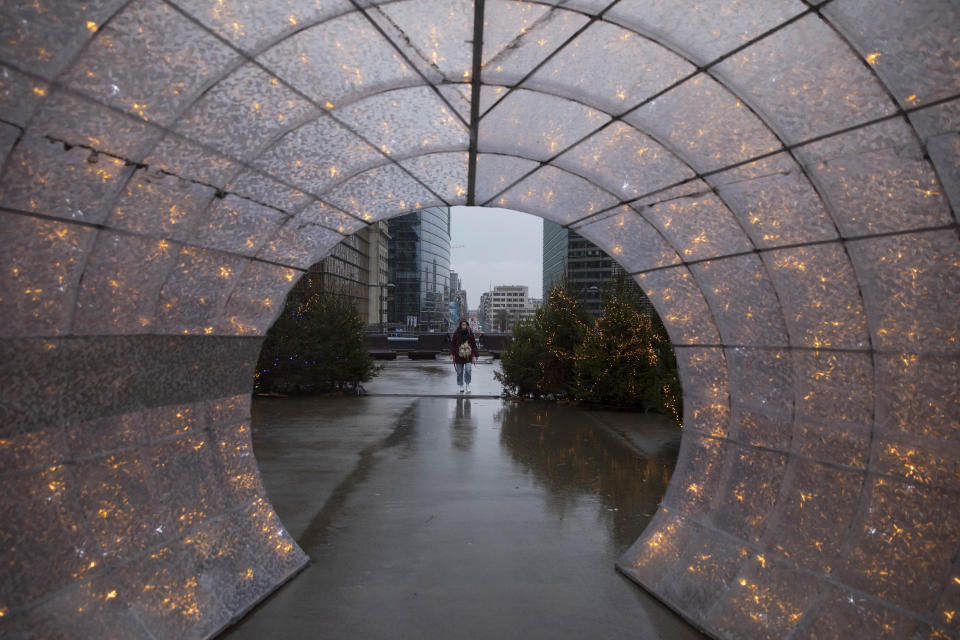 A woman walks amongst Christmas decorations outside of EU headquarters in Brussels, Wednesday, Dec. 23, 2020. France insisted on Wednesday that European Union negotiators should not yield to any time pressure imposed by the Jan. 1 economic cutoff date in the talks with Britain on a trade agreement in the wake of the Brexit divorce, arguing no deal would be better than a bad one. (AP Photo/Virginia Mayo)