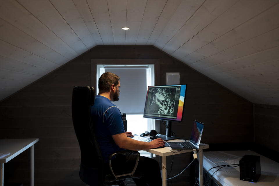 Garrett Fisher edits his photographs of glaciers in his rented home in Voss, Norway, on Aug. 3, 2022. (AP Photo/Bram Janssen)