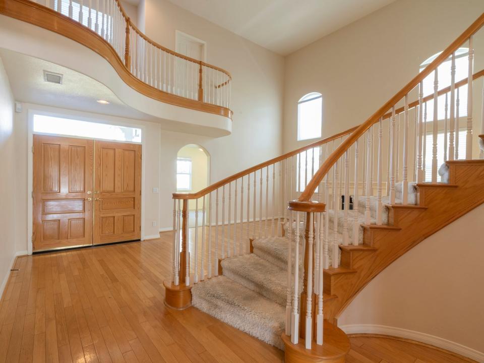 An entryway with curved stairs and a wooden double door.