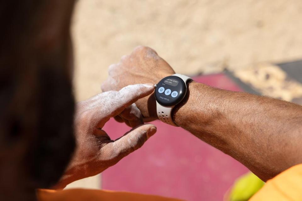 A person wearing a Google Pixel Watch 2 smartwatch and looking at the text message screen