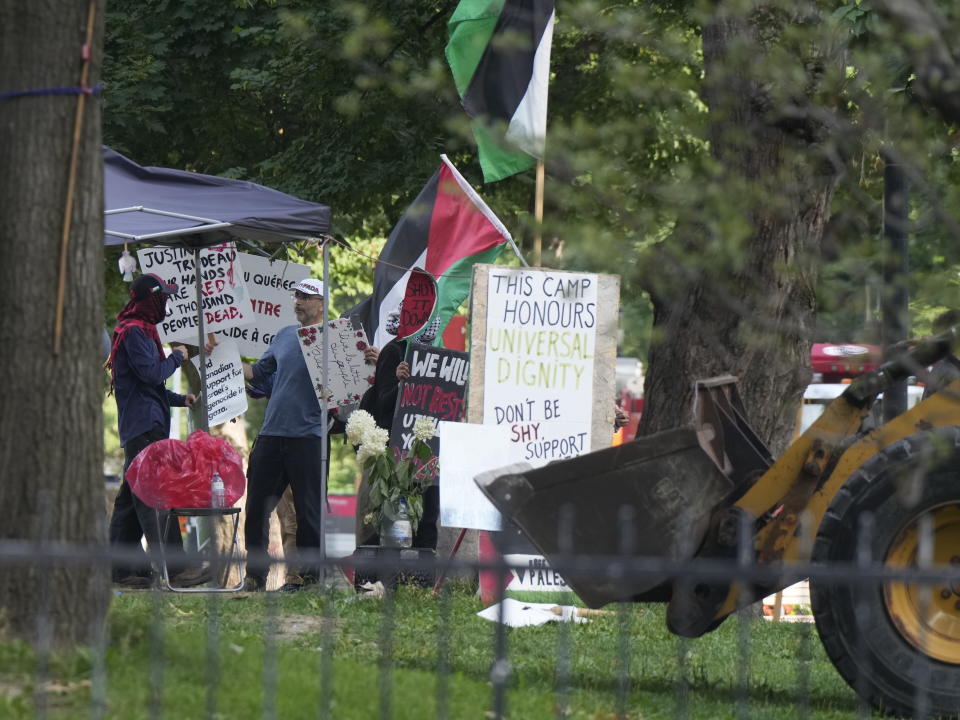 Protesters remove signs as bulldozers prepare to move in at McGill University in Montreal, Wednesday, July 10, 2024. The university closed its downtown campus as police descended in large numbers to help clear a pro-Palestinian encampment. (Ryan Remiorz/The Canadian Press via AP)