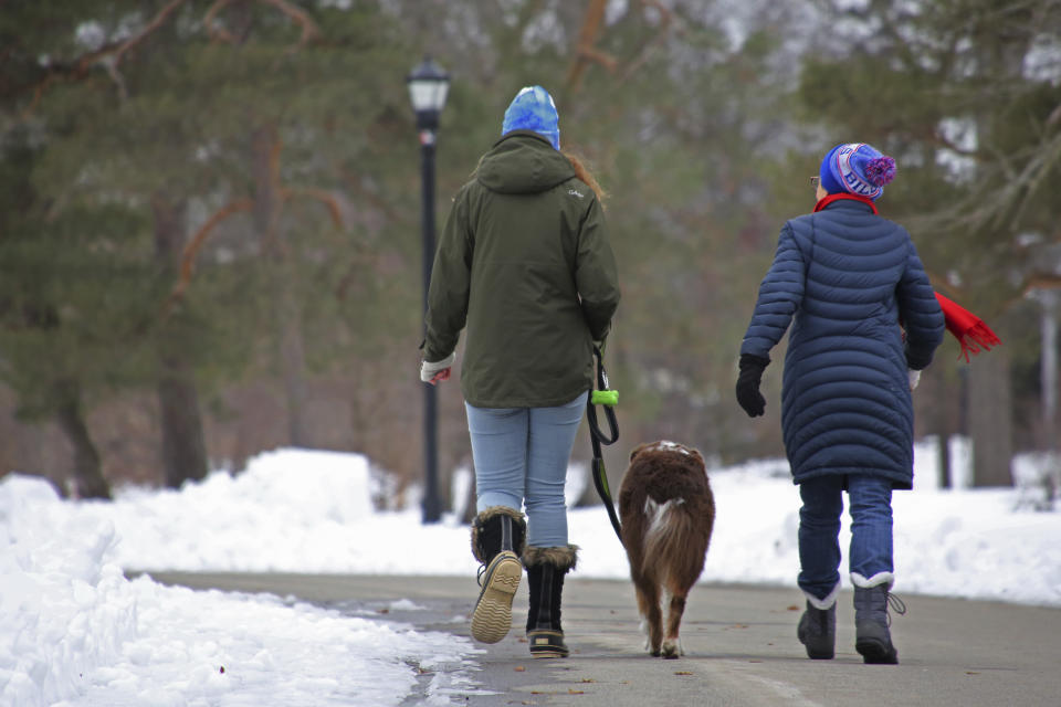 People take a dog for a walk in Delaware Park a few days after a winter storm rolled through western New York Thursday, Dec. 29, 2022, in Buffalo N.Y. (AP Photo/Jeffrey T. Barnes)