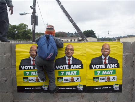 African National Congress (ANC) election posters featuring images of South Africa's President Jacob Zuma are displayed on a wall as a school boy climbs over it in Embo May 6, 2014. REUTERS/Rogan Ward