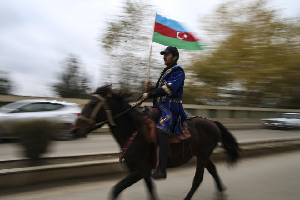 An Azerbaijani man holds a national flag riding a horse as he celebrates the transfer of the Lachin region to Azerbaijan's control, as part of a peace deal that required Armenian forces to cede the Azerbaijani territories they held outside Nagorno-Karabakh, in Aghjabadi, Azerbaijan, Tuesday, Dec. 1, 2020. Azerbaijan has completed the return of territory ceded by Armenia under a Russia-brokered peace deal that ended six weeks of fierce fighting over Nagorno-Karabakh. Azerbaijani President Ilham Aliyev hailed the restoration of control over the Lachin region and other territories as a historic achievement. (AP Photo/Emrah Gurel)