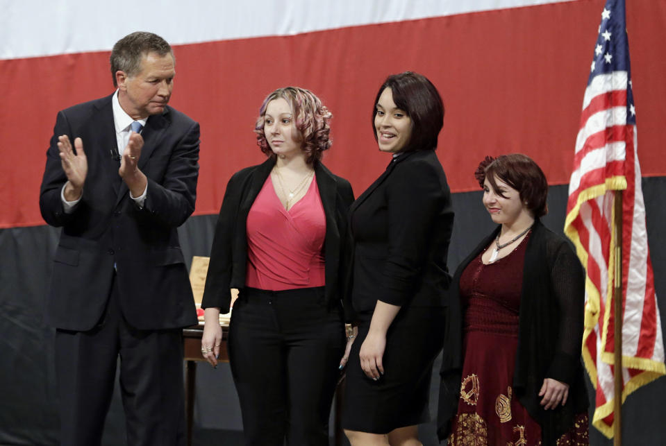 FILE- This Monday, Feb. 24, 2014 file photo shows Ohio Gov. John Kasich, from left, introducing Amanda Berry, Gina DeJesus and Michelle Knight during his State of the State address at the Performing Arts Center in Medina, Ohio. Berry broke through a screen door to freedom last May. Upstairs, officers found DeJesus and Knight. They had been snatched off the streets separately between 2002 and 2004 and locked inside Castro’s house where he chained and raped them, investigators later said. (AP Photo/Tony Dejak, File)