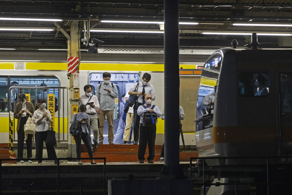 People wearing face masks wait for a train as it approaches a station in Tokyo, Thursday, Sept. 9, 2021. Japan announced Thursday it is extending a coronavirus state of emergency in Tokyo and 18 other areas until the end of September as health care systems remain under severe strain, although new infections have slowed slightly. (AP Photo/Hiro Komae)