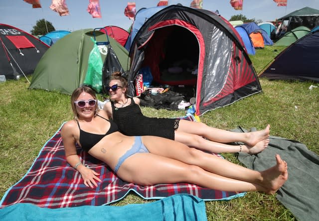 Festival-going sisters Hanna (bottom) and Emma Ahlberg sunbathe in the hot weather on the third day of the Glastonbury Festival at Worthy Farm in Somerset