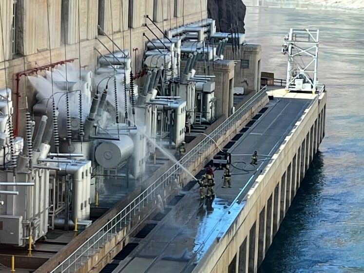 En esta imagen proporcionada por la Oficina de Recuperación de Estados Unidos, los bomberos extinguen un incendio en la presa Hoover que limita con Nevada y Arizona el martes 19 de julio de 2022, cerca de Boulder City, Nev. (Oficina de Recuperación de Estados Unidos vía AP)