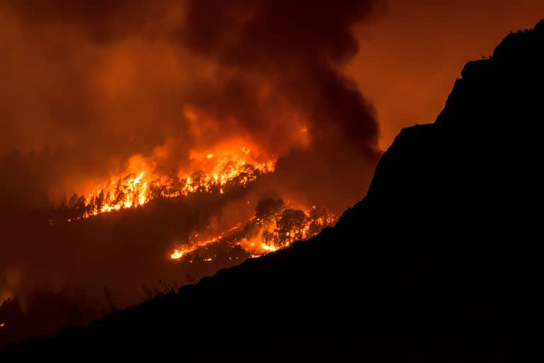 En esta imagen tomada desde el pueblo de Sobradillo, el 16 de agosto de 2023, un incendio forestal arrasa una zona boscosa de la isla canaria de Tenerife