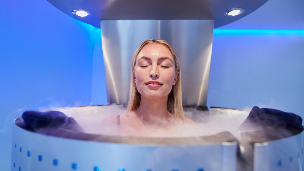  Woman in a cryotherapy chamber during treatment standing with eyes closed. 