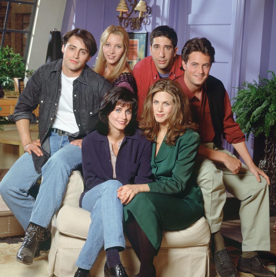 courtney cox, matt leblanc, lisa kudrow, david schwimmer, matthew perry, and jennifer aniston sit on a large armchair in a living room