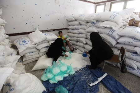 Women weigh the aid provided by the World Food Programme (WFP) for distribution in Sanaa