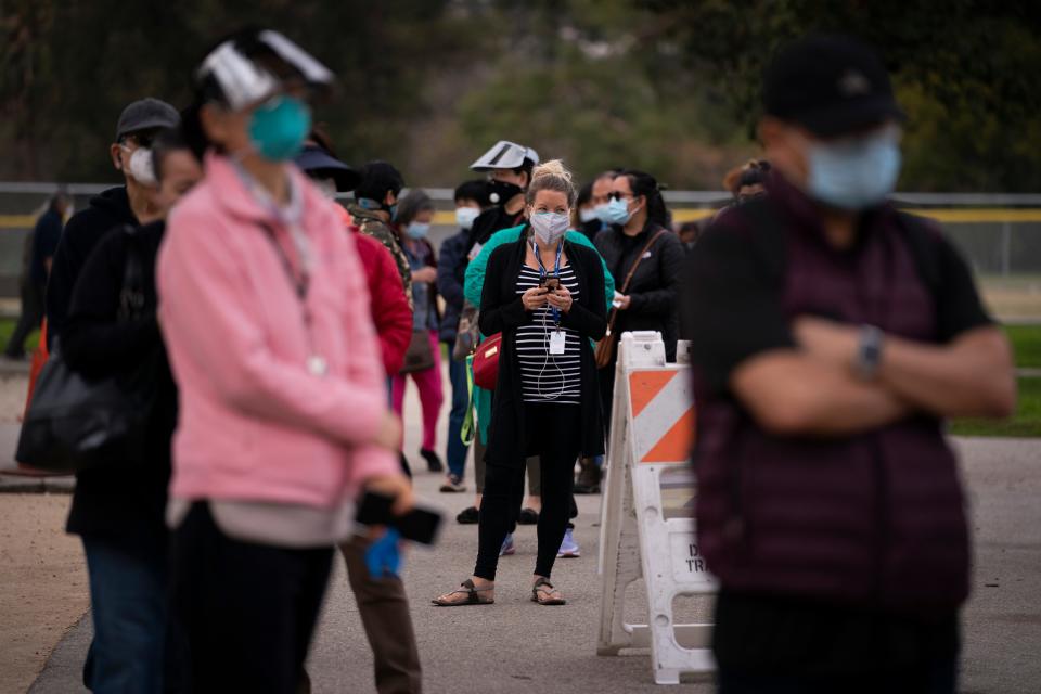 People wait in line to get COVID-19 vaccinations on Tuesday in a park in the Lincoln Heights neighborhood of Los Angeles.