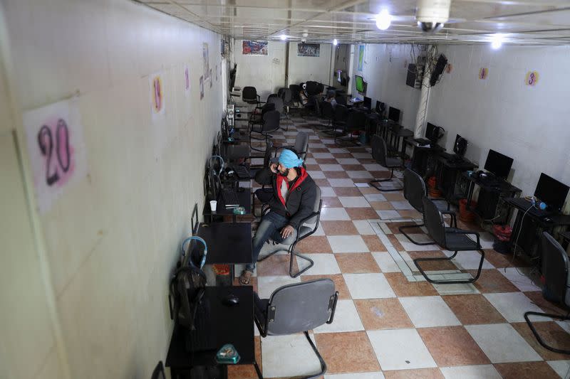 Man talks on a mobile phone as he sits in an empty internet cafe amid an internet service cut in Sanaa