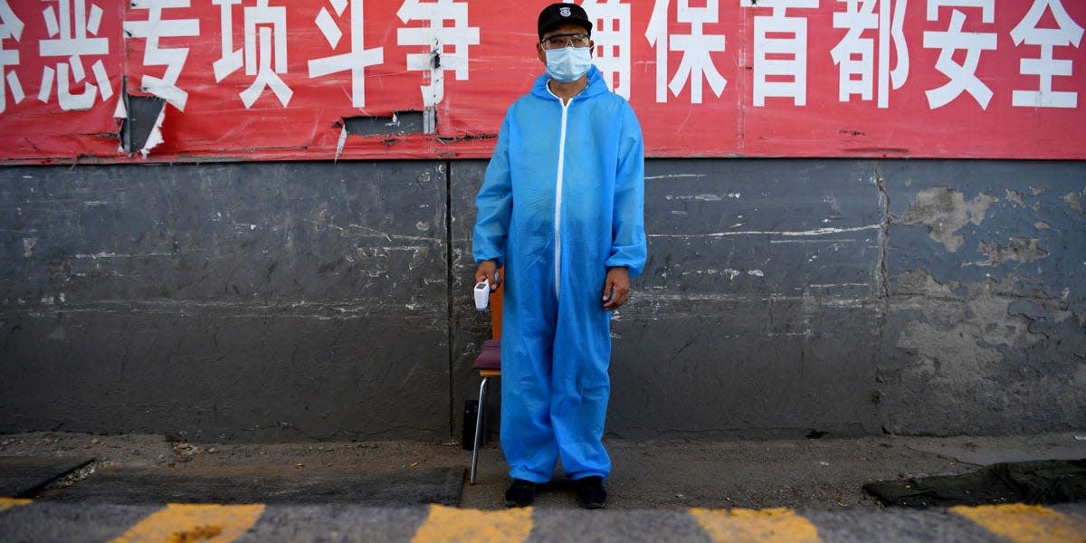 A security guard wearing a protective mask and suit stands at a checkpoint at the Xinfadi market in Beijing, China, on June 14, 2020.