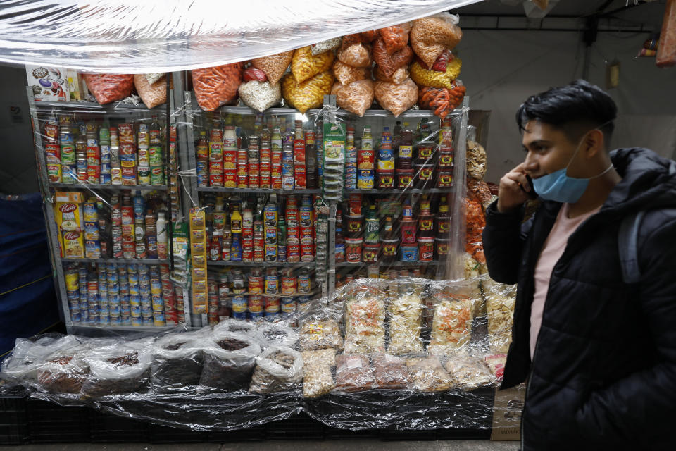 A man walks past goods covered in plastic to protect against possible rain, at Mercado San Cosme, where some vendors decided to put in place protective measures against coronavirus while others continue to work without masks or barriers, in Mexico City, Thursday, June 25, 2020. (AP Photo/Rebecca Blackwell)