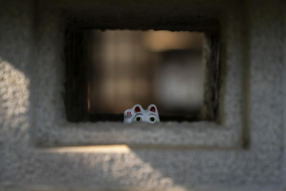 In this June 25, 2019, photo, a small beckoning cat figurine is placed inside a stone lamp at Gotokuji Temple in Tokyo. According to a centuries-old legend provided by the temple, Gotokuji, a Buddhist temple located in the quiet neighborhood of Setagaya, is the birthplace of beckoning cats, the famous cat figurines that are widely believed to bring good luck and prosperity to home and businesses. Some visitors come just to snap a few photos, while others make a trip to the temple to pray and make wishes. (AP Photo/Jae C. Hong)