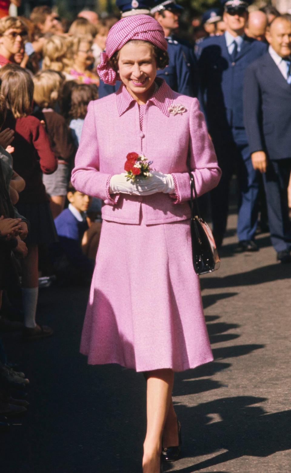 Queen Elizabeth ll, wearing a lilac suit with a checked collar and matching turban-style hat, during a walkabout in Wellington, New Zealand, 27th February 1977. The visit is part of the Queen's Silver Jubilee tour