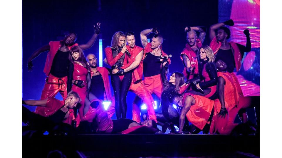 Girls Aloud on stage with dancers in red costumes