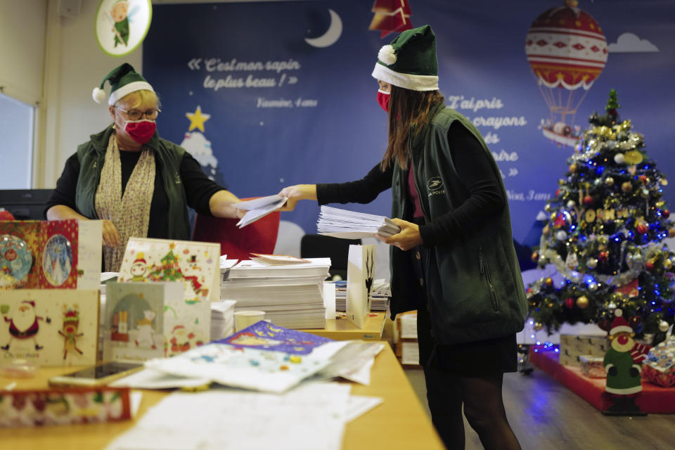 Postal workers who call themselves "Elves" sort envelopes addressed to "Pere Noel" - Father Christmas in French - decorated with love hearts, stickers and glitter, in Libourne, southwest France, Monday, Nov. 23, 2020. Letters pouring by the tens of thousands into Santa's mailbox offer a glimpse into the worries and hopes of children awaiting a pandemic-hit Christmas. Along with usual pleas for toys and gadgets, kids are also mailing requests for vaccines, for visits from grandparents, for life to return to the way it was. The office estimates that one letter in three mentions the pandemic. (AP Photo/Francois Mori)