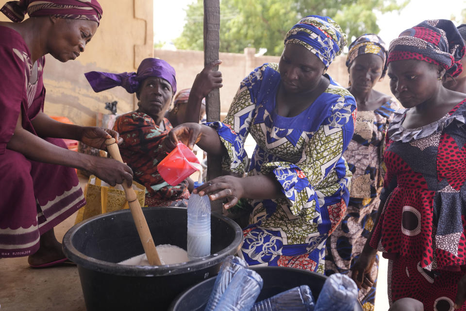 Women fill a plastic bottle with a nutritious soya beans drink in Kaltungo Poshereng Nigeria, Sunday, June 2, 2024. More than a dozen women gathered this week in Kaltungo's Poshereng village where they are learning at least 200 recipes they can prepare with those local foods which, in the absence of rain, are grown in sand-filled sacks that require small amounts of water. The training session mirrored the struggles of households who are more challenged amid Nigeria's worst cost of living crisis. (AP Photo/Sunday Alamba)