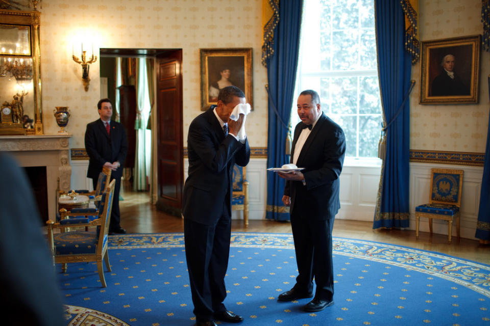 Obama wipes his face with a cloth handed to him by White House butler Von Everett in the Blue Room of the White House following an event with business leaders in the East Room on Jan. 28, 2009.