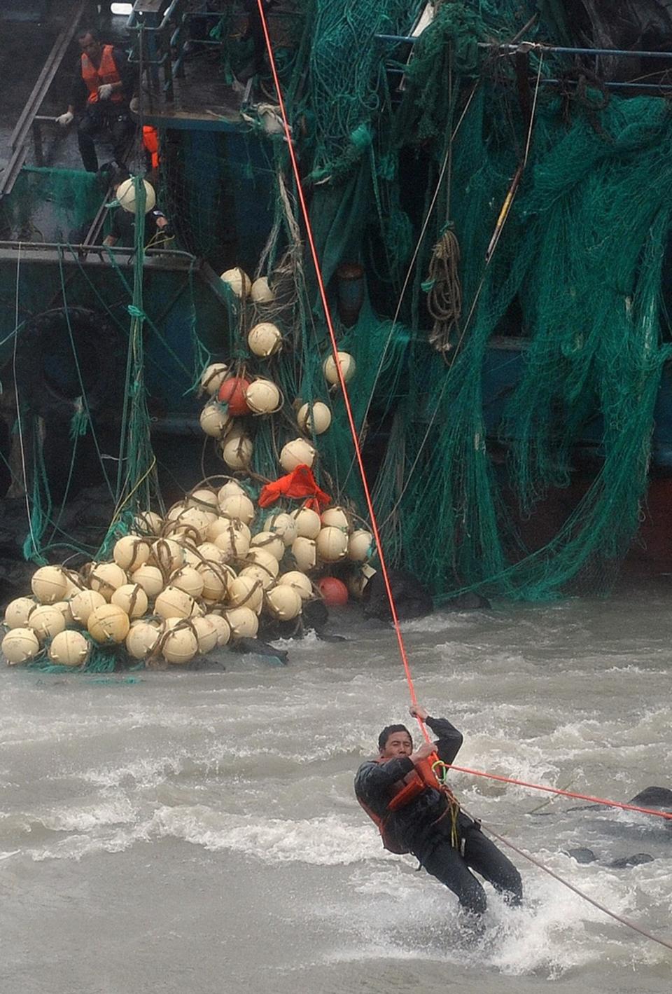 A Chinese fisherman is rescued by South Korean coast guard officers from a Chinese ship that ran aground in Jeju, South Korea, Tuesday, Aug. 28, 2012. A powerful typhoon pounded South Korea with strong winds and heavy rain Tuesday, while the nation's coast guard battled rough seas in a race to rescue fishermen on two Chinese ships that slammed into rocks off the southern coast. (AP Photo/Newsis, Kang Jae-nam) KOREA OUT