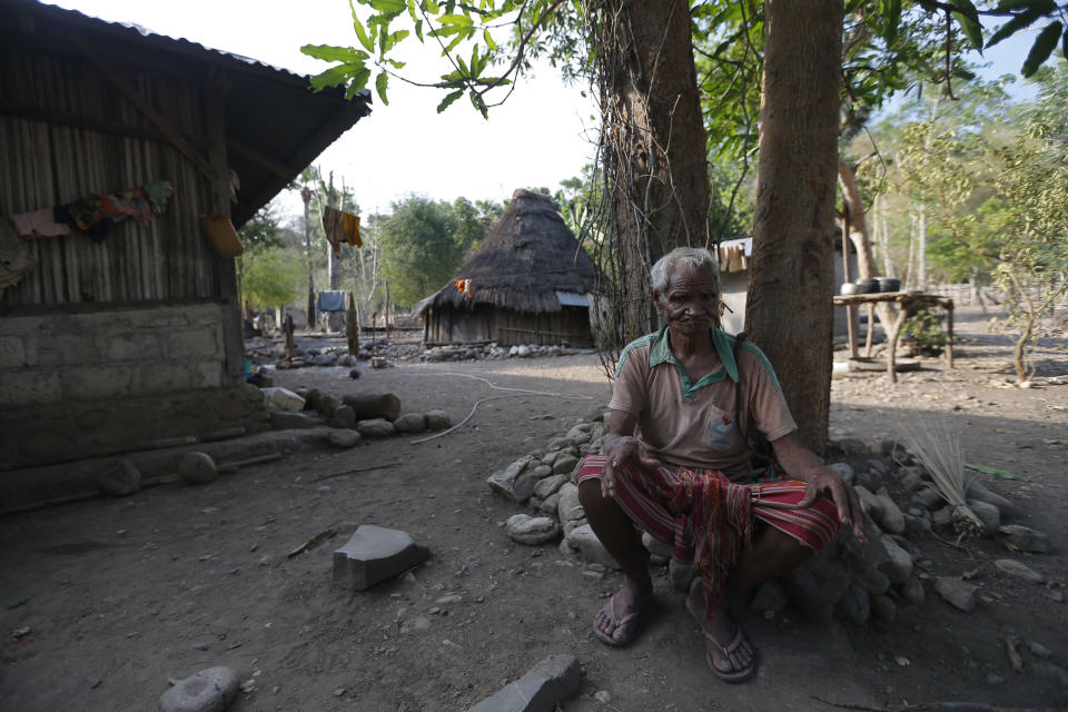 In this Oct. 23, 2018, photo, Laurencius Kollo, great-uncle of Marselina Neonbota, rests outside his home in Fatukoko village in West Timor, Indonesia. Marselina left home eight years ago for a job in Malaysia, a place where some Indonesian migrant workers can earn more money in a few years than in a lifetime at home. She never returned. (AP Photo/Tatan Syuflana)