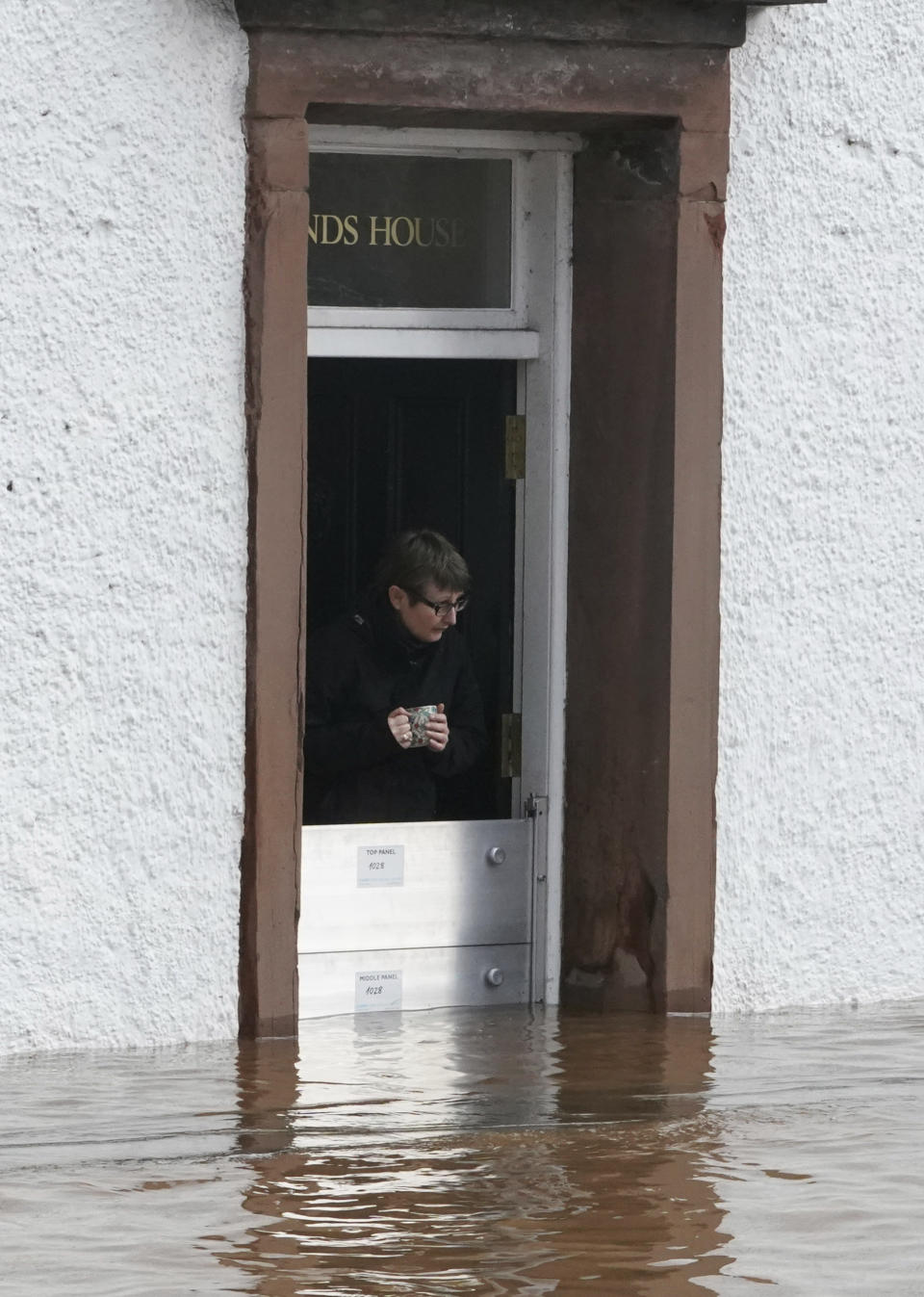 A woman looks out at the flood water at a property, in Appleby-in-Westmorland, as Storm Ciara hits the UK, in Cumbria, England, Sunday Feb. 9, 2020. Trains, flights and ferries have been cancelled and weather warnings issued across the United Kingdom as a storm with hurricane-force winds up to 80 mph (129 kph) batters the region. (Owen Humphreys/PA via AP)