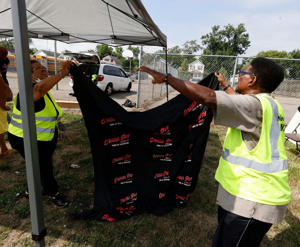 (L to R) Janice Waters, 71 of Detroit helps James Ford, 75, of Detroit, hang up an Obama Day blanket to shield people from the sun before the start of the "Obama Weekend Festival" that Ford organized at the Barack Obama Leadership Academy in Detroit on Friday, Aug. 5, 2022. Waters, the director of the festival, and Ford, its founder, put together this event as part of an extension of ARISE Detroit! Neighborhoods Day.