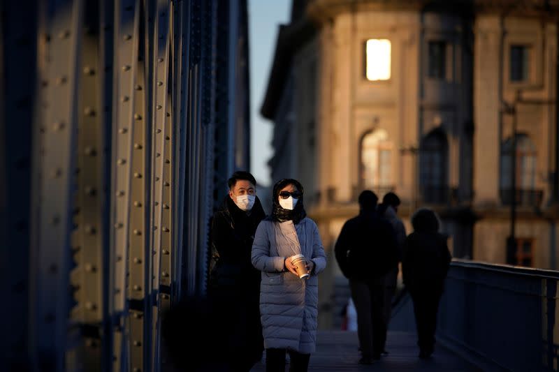People wearing masks walk on a bridge in Shanghai