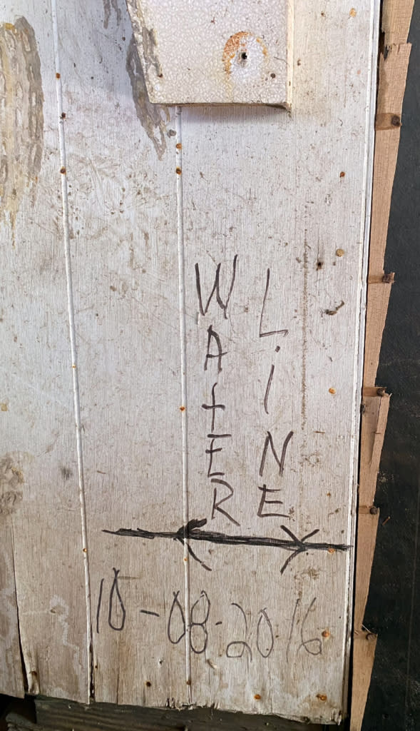 a wall on a hurricane-damaged home with the handwritten words "waterline"