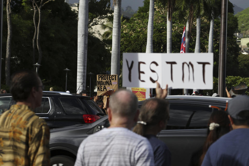 Supporters of the Thirty Meter Telescope, foreground, gather for a rally outside the Hawaii State Capitol in Honolulu on Thursday, July 25, 2019, as opponents of the telescope gather across the street. Supporters said the giant telescope planned for Hawaii's tallest mountain will enhance humanity's knowledge of the universe and bring quality, high-paying jobs, as protesters blocked construction for a second week. (AP Photo/Audrey McAvoy)