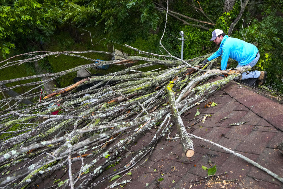 Isiah Turner, a volunteer with Trae the Truth's Relief Gang, cuts branches from a tree that fell onto the roof of Carrie Turner's home after a severe storm, Friday, May 17, 2024 in Houston. (Brett Coomer/Houston Chronicle via AP)