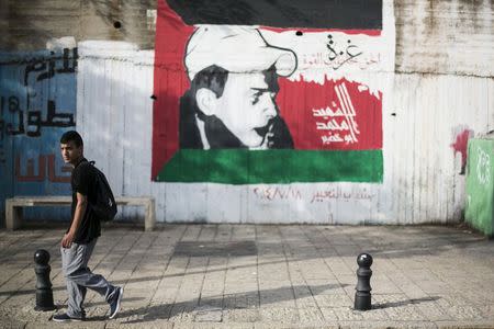 A youth walks past graffiti depicting Mohammed Abu Khudair, who was killed in a revenge attack by Israelis in 2014, on a street in Nazareth, northern Israel October 12, 2015. REUTERS/Baz Ratner