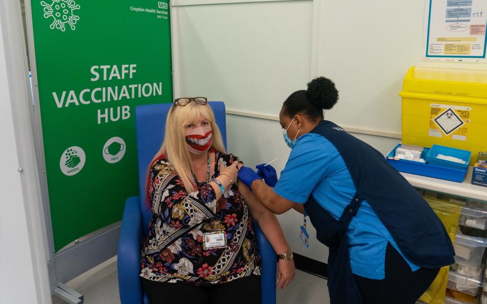 ...while Yvonne Woods wore a happy face mask to receive her booster - PA