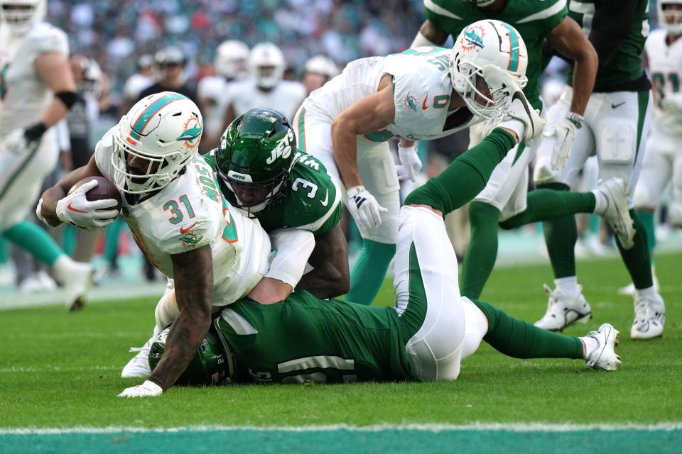 Miami Dolphins running back Raheem Mostert (31) gains a few tough yards as New York Jets safety Jordan Whitehead (3) and safety Ashtyn Davis (21) converge on the play during the first half of an NFL game at Hard Rock Stadium in Miami Gardens, Dec. 17, 2023.