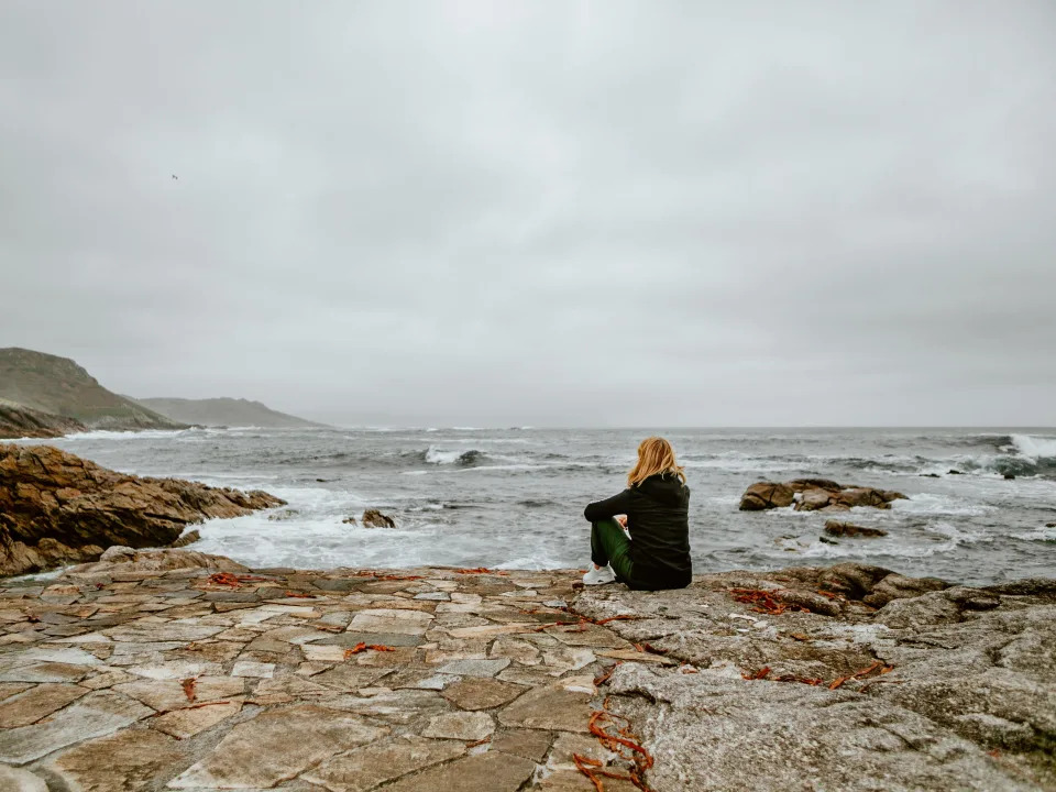 One woman standing on the rock looking out the waves and the sea