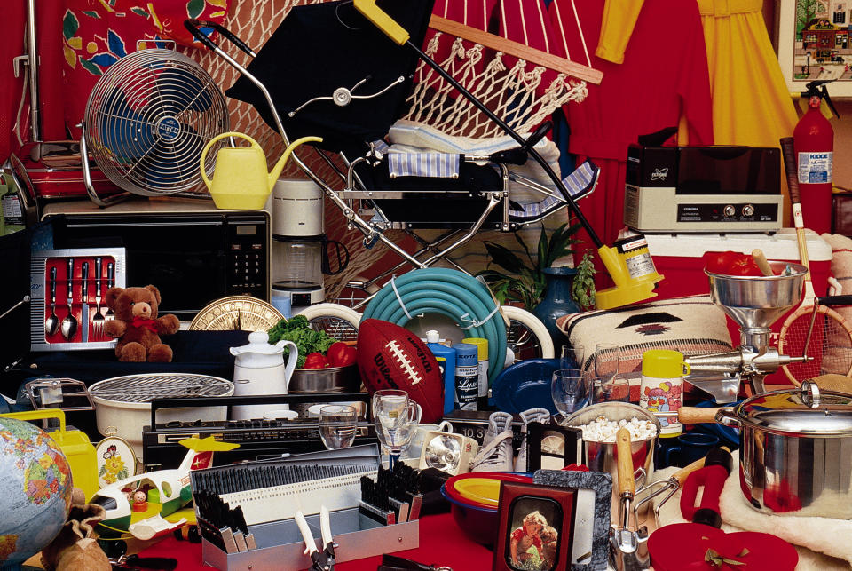 An image shows a chaotic array of household items, including a microwave, fan, hammock, pool hose, toy football, pots, kitchen utensils, and various other random objects